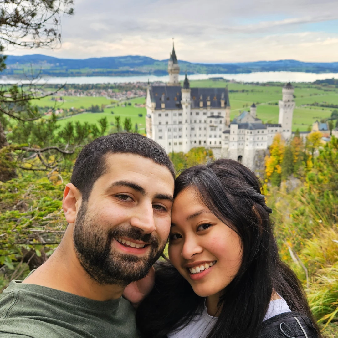 Tim and Zoe smiling with Neuschwanstein Castle in the background.