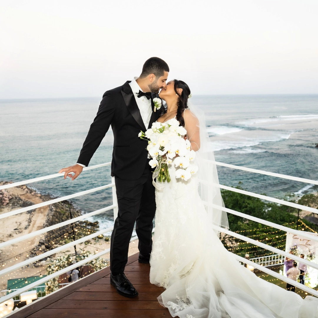 Tim and Zoe on their wedding day on the balcony of their wedding chapel overlooking the ocean in Bali, Indonesia.