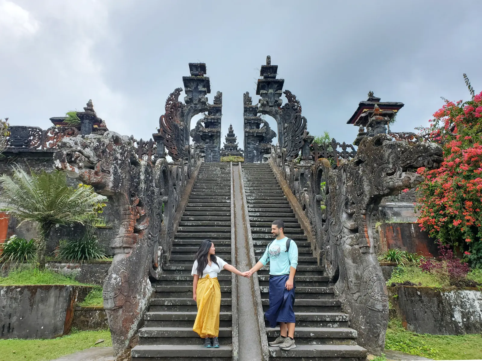 Tim and Zoe holding hands at the bottom of the entrance stairs to the Besakih Great Temple in Sidemen, Bali, Indonesia.
