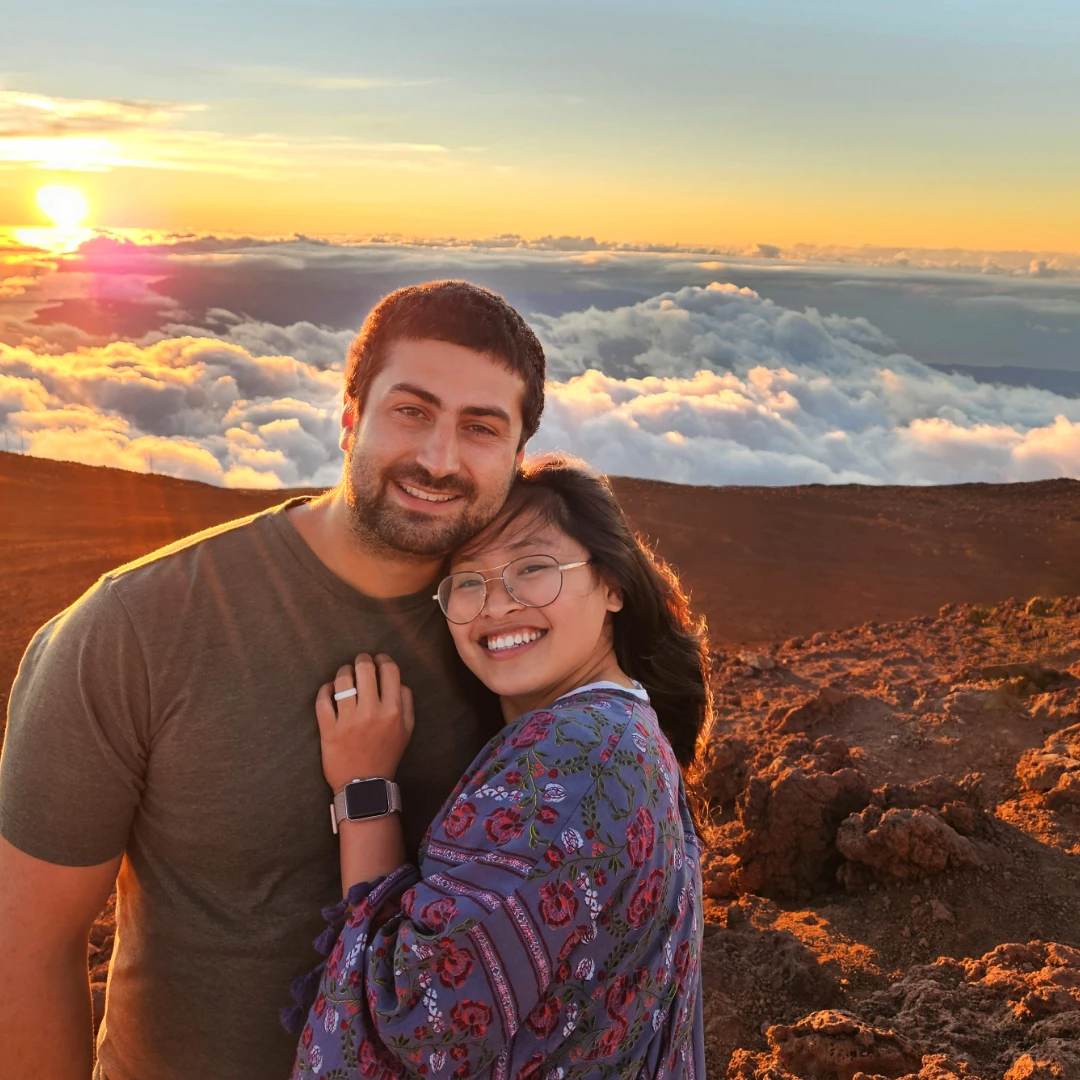 Tim and Zoe posing in front of a beautiful sunset view on the top of Haleakala Volcano in Maui, Hawaii.