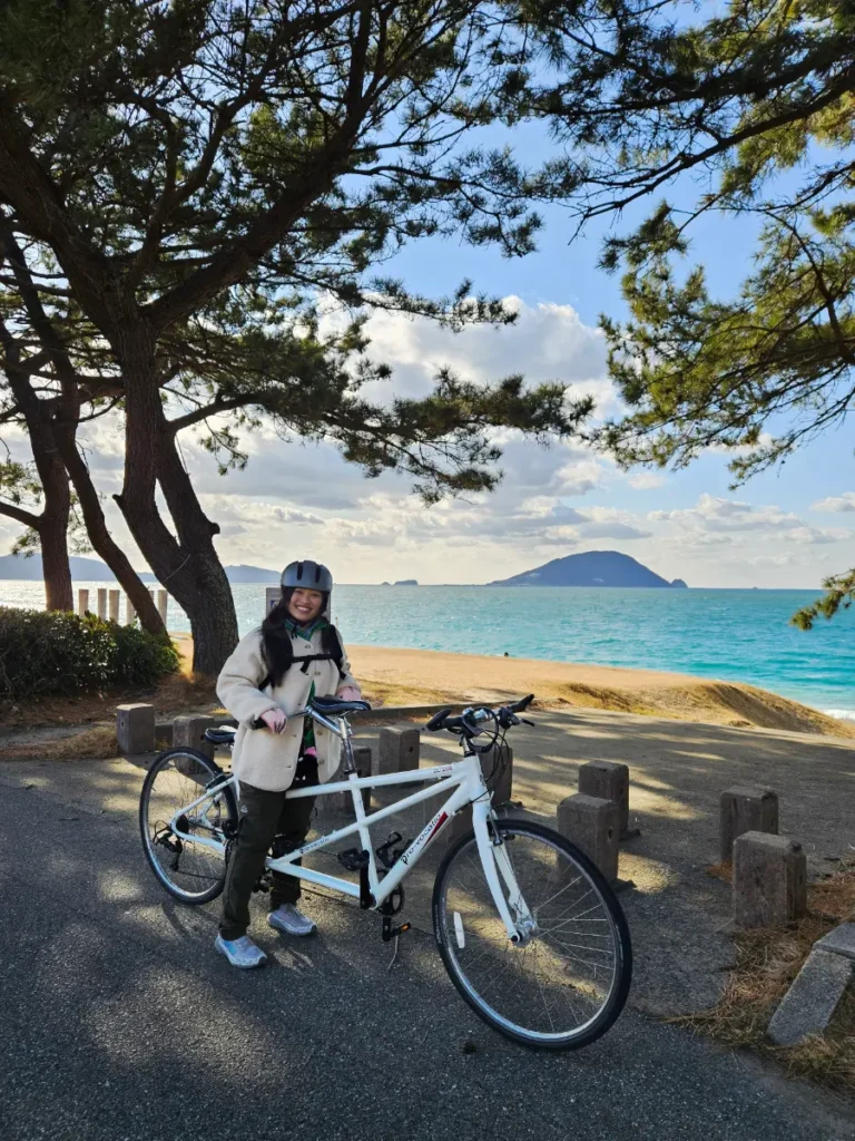 Zoe posing with the tandem bike at Katsuma Beach in Shikanoshima.