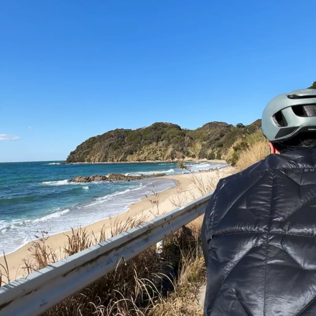 Tim biking by the ocean under the blue sky in Shikanoshima.