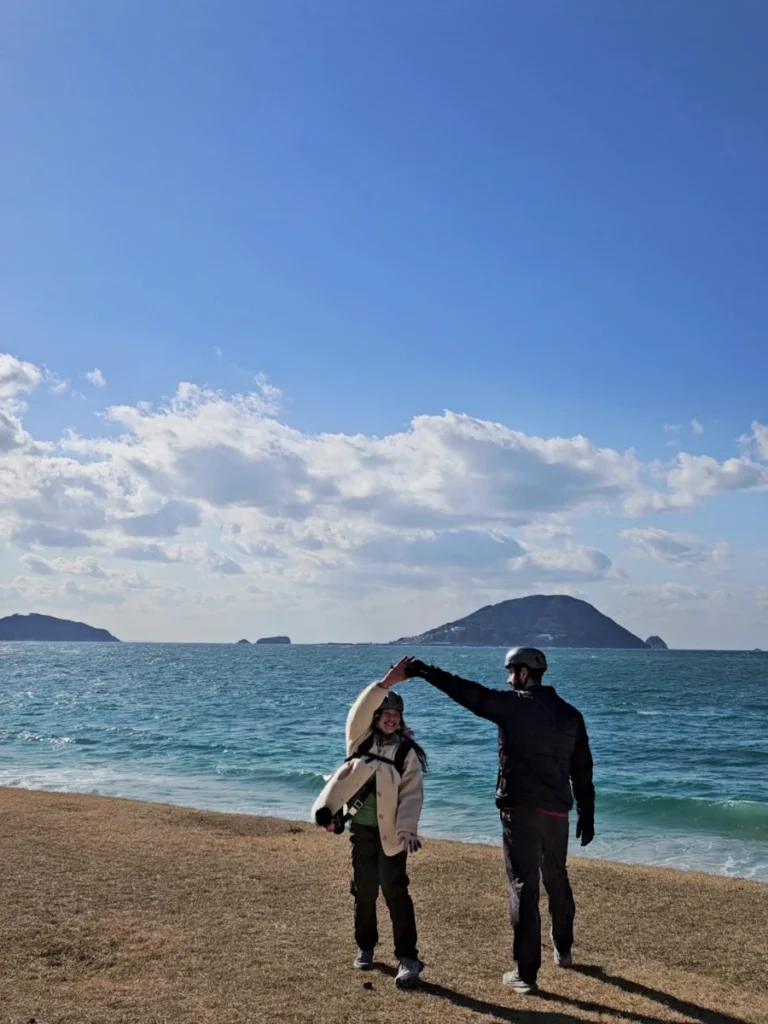 Tim and Zoe dancing at Katsuma Beach with the ocean in the background.