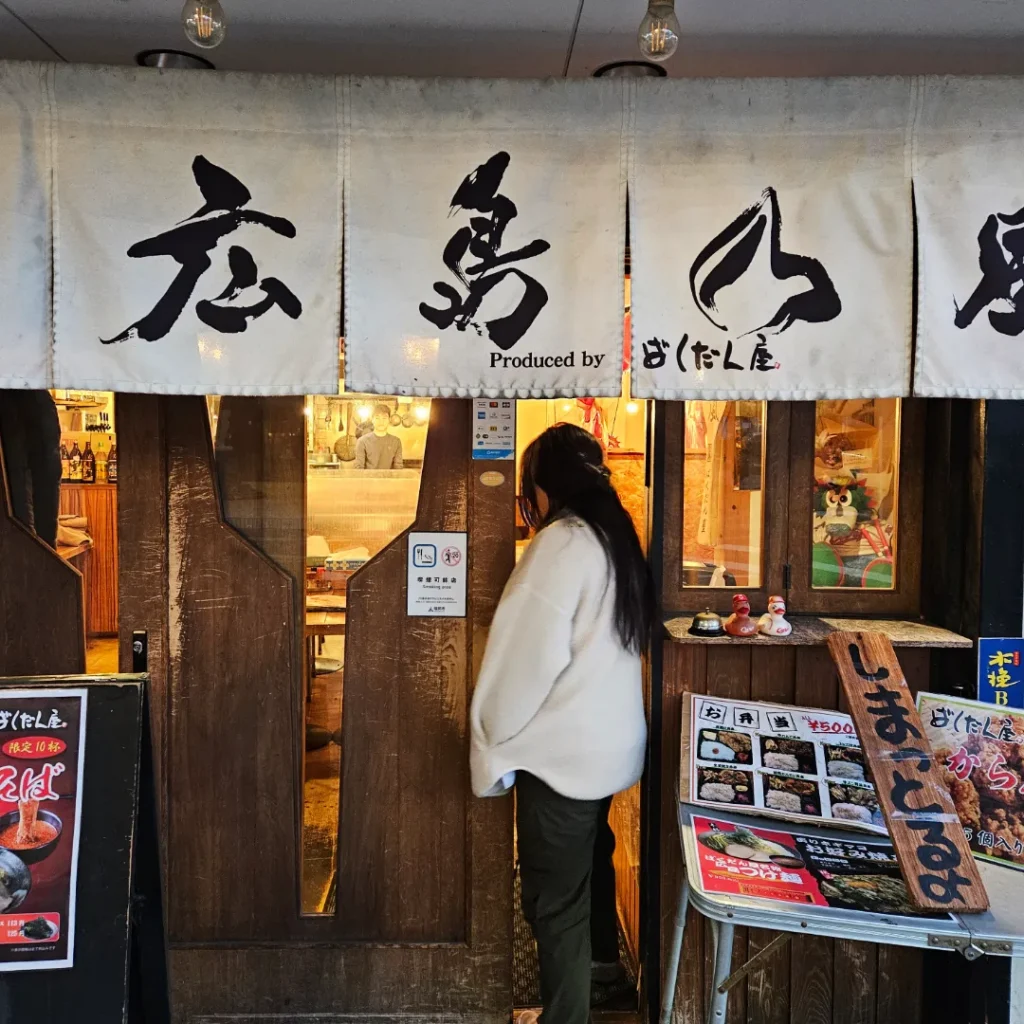 Zoe sliding open a wooden door into a Japanese restaurant.