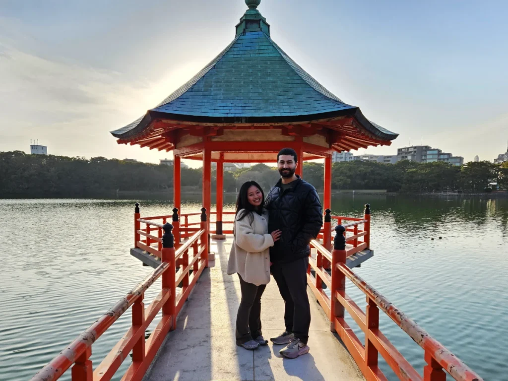 Tim and Zoe standing in front of a pagoda overlooking Ohori Lake