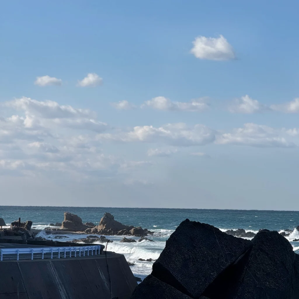 A view of the open sky and waves hitting the rocks from the Kurose viewpoint in Shikanoshima.