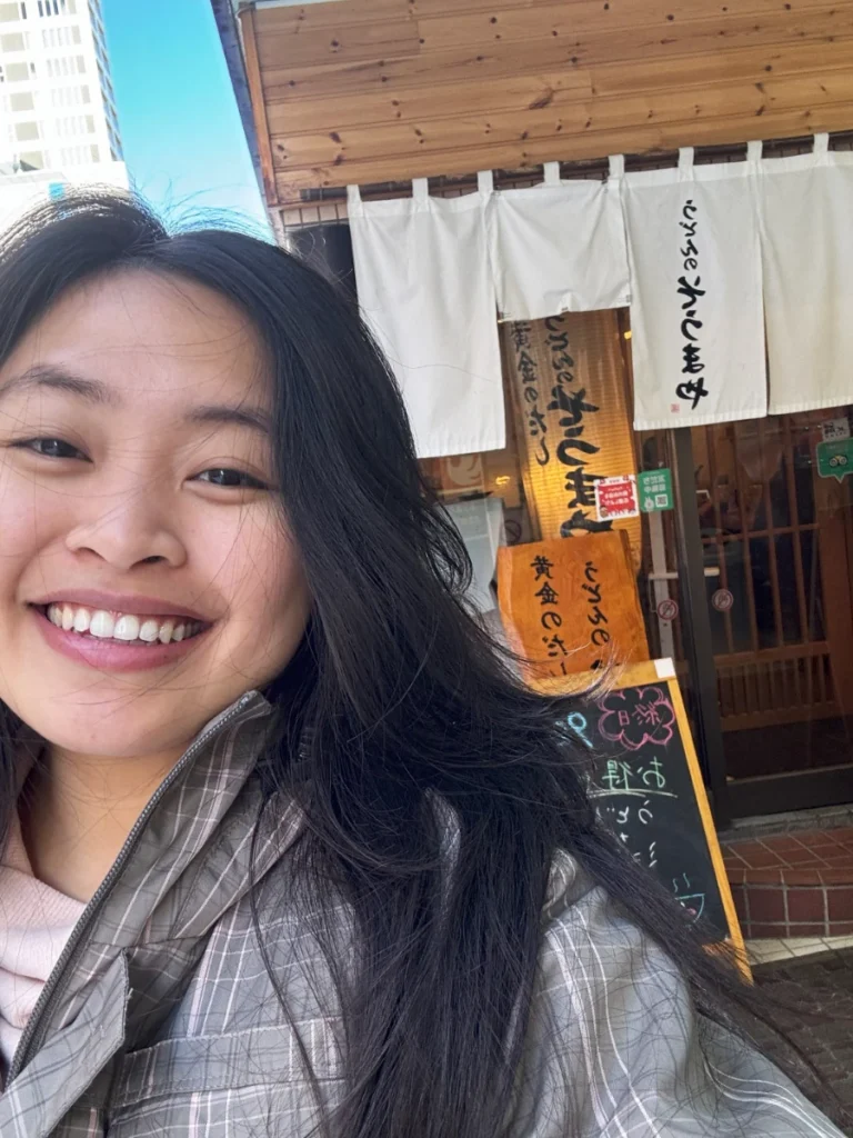 Zoe taking a selfie in front of her favorite udon shop in Japan, Soumaya Udon.