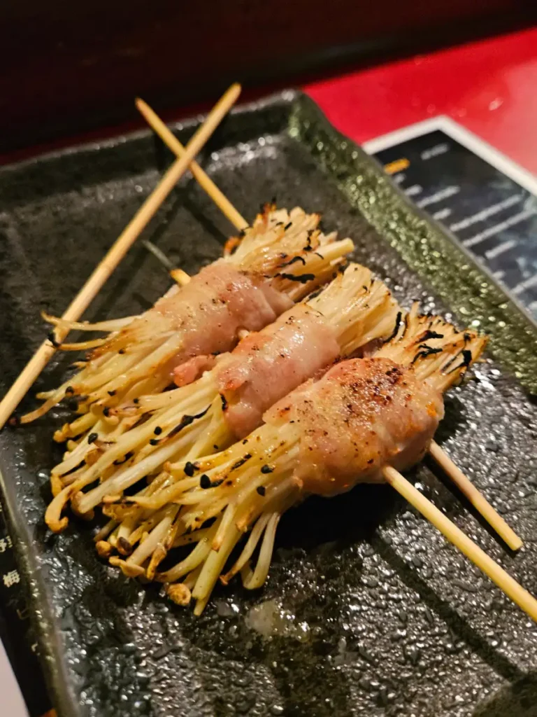 Charcoal grilled yakitori of enoki mushroom wrapped in pork belly.
