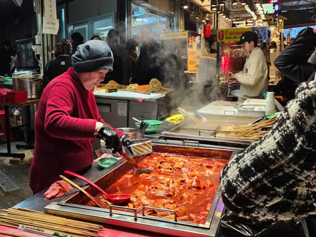 Delicious looking food stall serving bright red Korean spicy rice cakes and fish cakes.