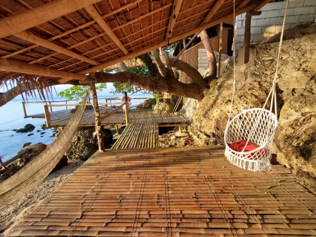 A beautiful brown bamboo deck with a hammock and chair swing overlooking the ocean of Cebu.