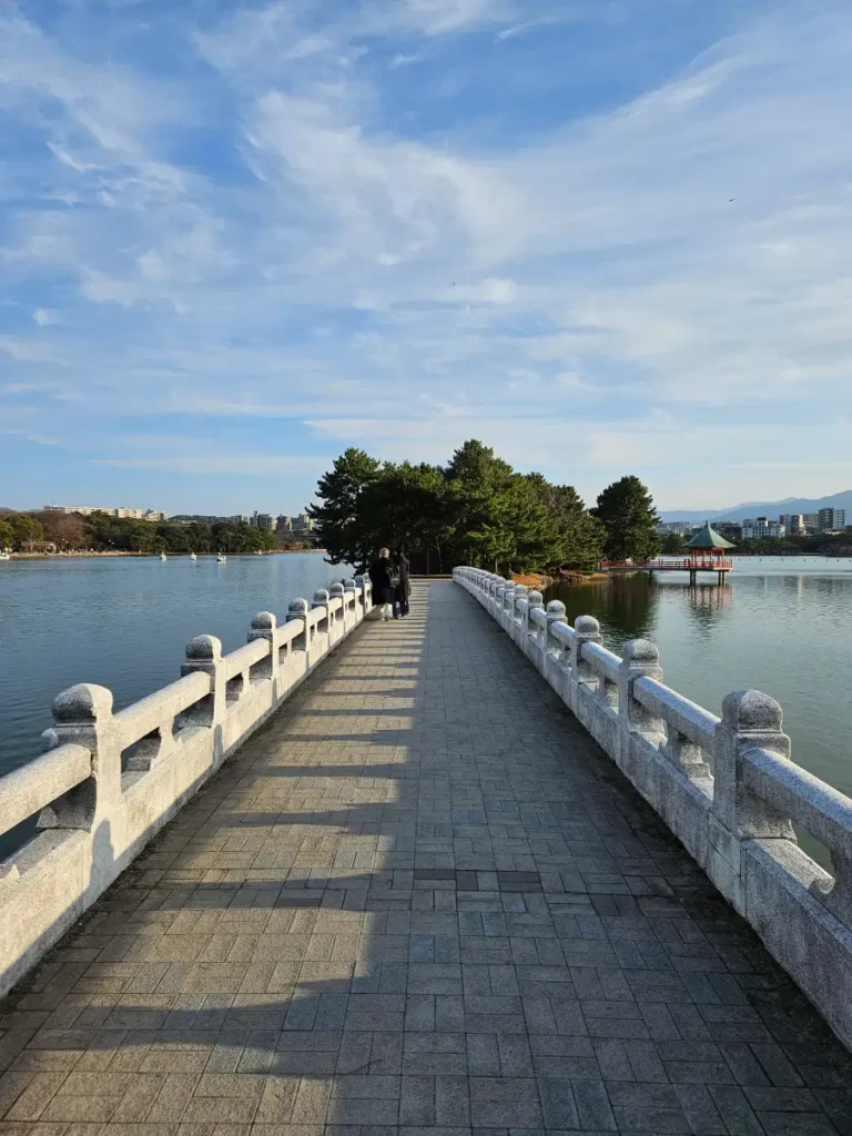 Bridge to island in the middle of Ohori Pond with views of a Japanese pagoda.