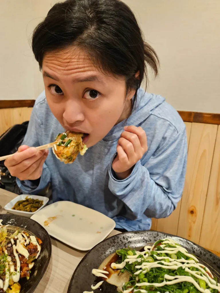 Zoe taking a bit from a freshly fried takoyaki ball.