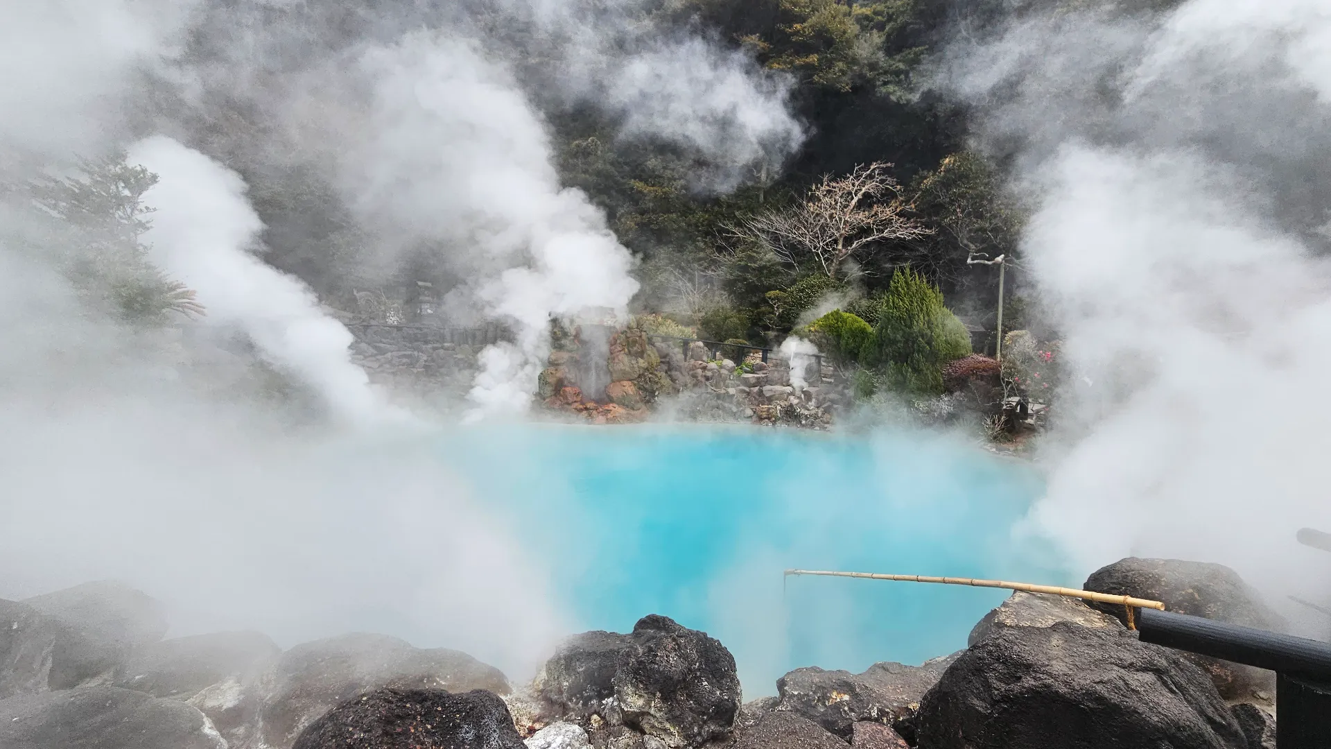 The steaming blue waters of Umi Jigoku hot spring in Beppu, a highlight of our Kyushu onsen travel guide, with thick white clouds of steam rising from the vibrant azure surface.