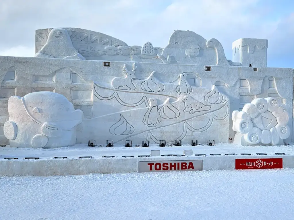 A massive, intricately carved snow stage featuring different characters at the Asahikawa Winter Festival during a winter in Hokkaido.