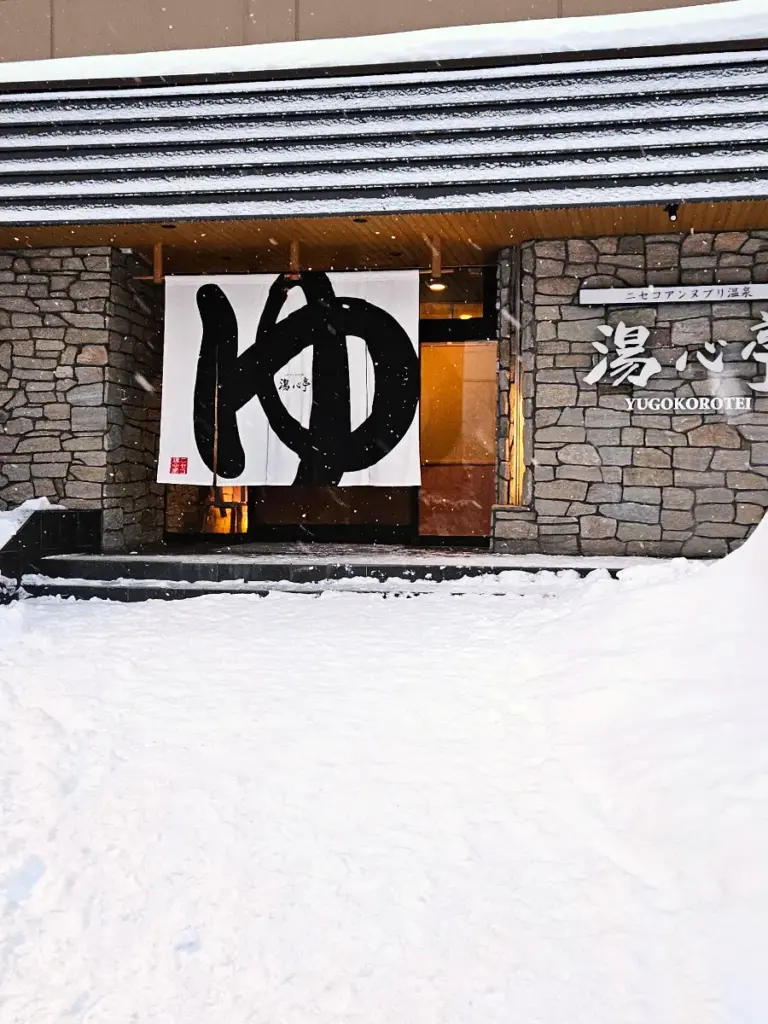 The entrance to our ryokan in Niseko, featuring a white curtain with the Japanese character for hot spring.