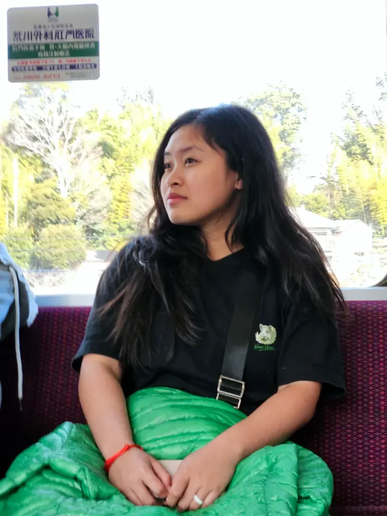 Zoe sitting quietly on a Japanese train and looking out the window at the passing scenery.