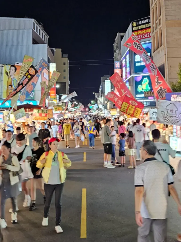 Crowds of people walking through the bright, bustling stalls of the Wenhua Road Night Market in Chiayi.