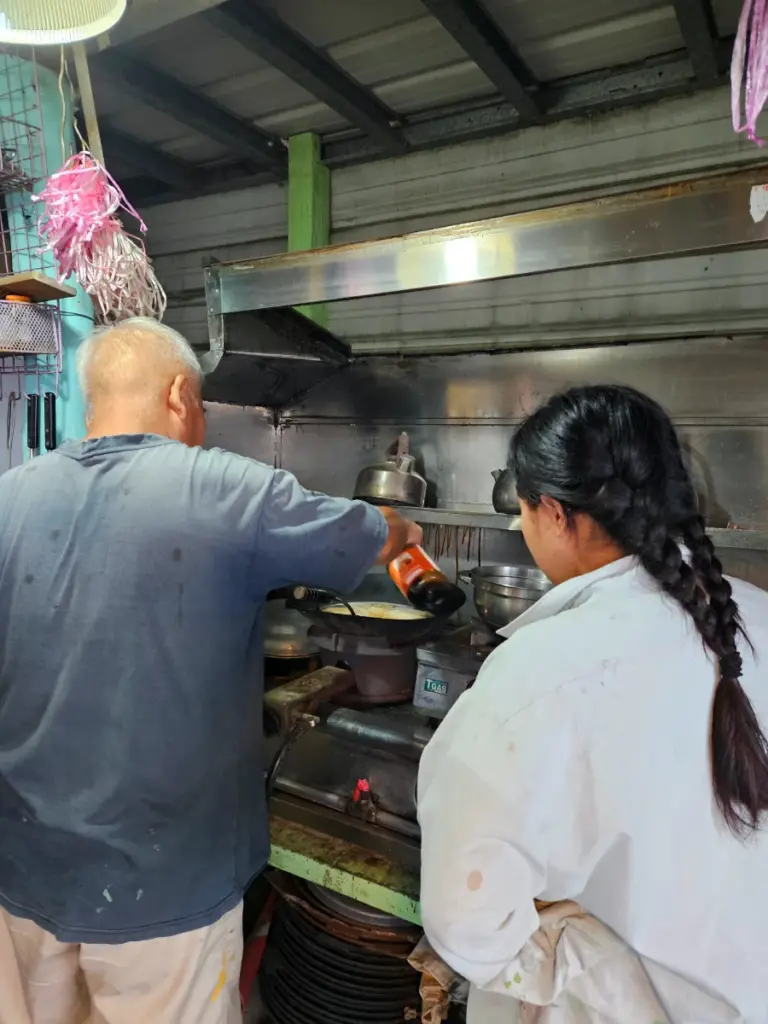 Steve cooking dinner in his outdoor kitchen while Zoe watches, a highlight of our Workaway experience in Taiwan.