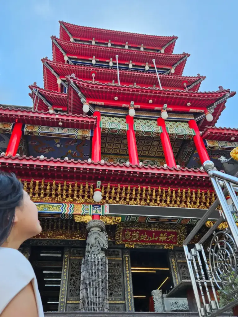 Zoe looking up at the ornate, multi-storied red and gold architecture of the Jiuhua Mountain Temple in Chiayi.
