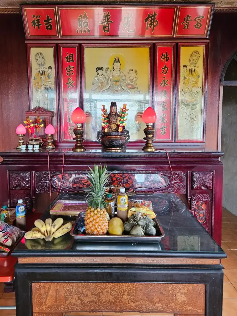 A traditional household altar beautifully decorated with zongzi, pineapples, bananas, and lit lotus lamps for the Dragon Boat Festival.