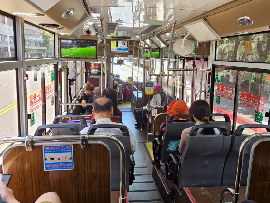 Interior view of commuters sitting inside a clean and spacious local public bus navigating the streets of Taipei.