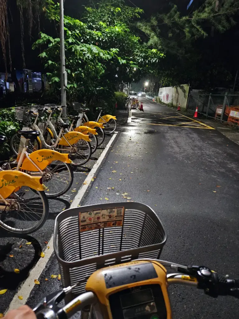 A row of bright yellow and white YouBike 2.0 bicycles parked cleanly at a street-side docking station in Taipei at night.