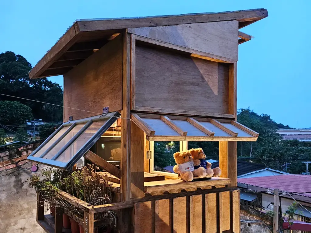 A cozy wooden display house featuring teddy bears at Treasure Hill Artist Village overlooking the village at dusk.
