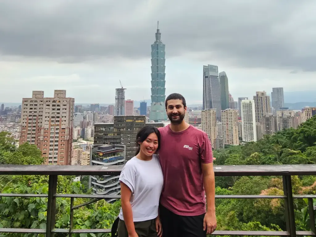 Zoe and Tim taking a photo at a viewing platform on the Elephant Mountain hike with Taipei 101 in the background.