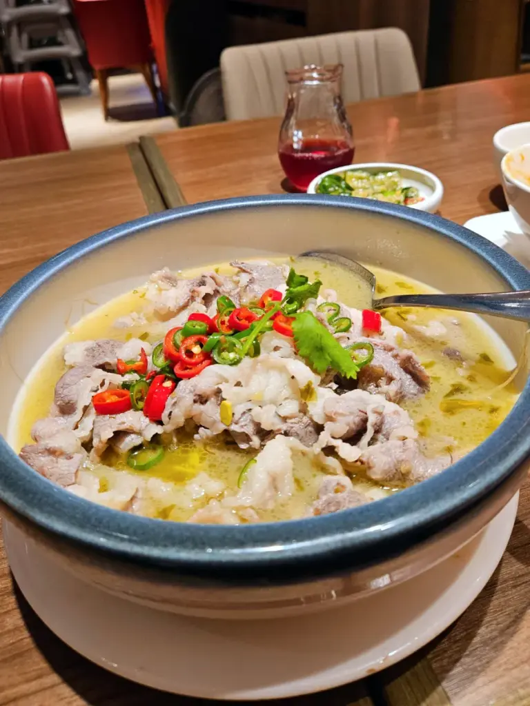A bowl of spicy Sichuan beef broth with fresh chilies from Kaifun Breeze, a post-hike dinner in the Taipei 101 area.
